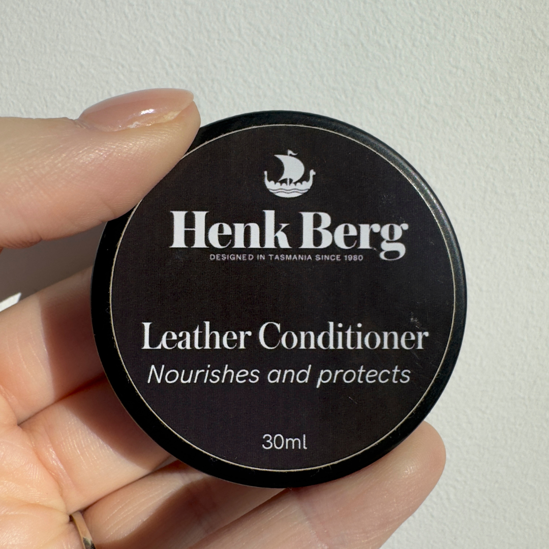 Henk Berg Leather Conditioner jar in hand, nourishes and protects vegetable-tanned leather, ideal for leather purses.